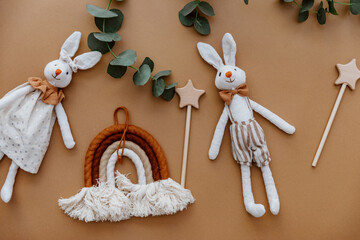 Two rabbits, rainbow and wooden toys on brown background. Top view, flat lay