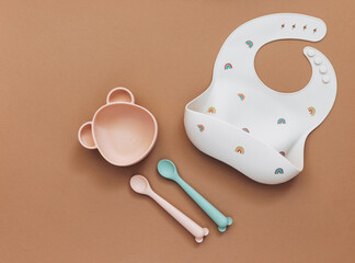 Cute baby bib for food on brown light background, top view, copy space, Bright baby tableware and...