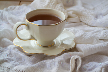 Antique porcelain tea cup full of tea on white vintage background