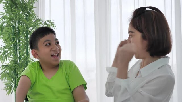 Happy Asian Family Mother And Son With Disability In A Wheelchair Clapping Hands To Encouragement At Home. Supportive, Care, Coexistence Slow Motion Shot