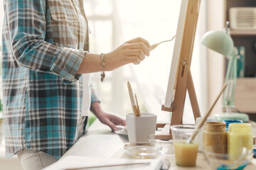 Artist working in the atelier and painting with a spatula