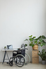 Vertical background image of empty armchair by home office workplace in minimal interior against white wall, copy space