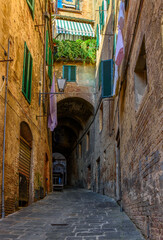 Medieval narrow street in Siena, Tuscany, Italy. Architecture and landmark of Siena. Cozy cityscape of Siena