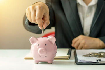 Business women put money coins into piglets to save money and financial and saving ideas for a...