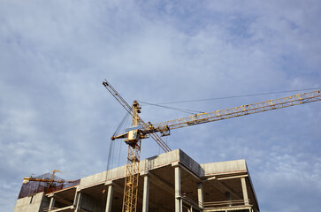 Fototapeta na wymiar Tower crane building a house. Concrete building under construction