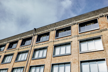 Fototapeta premium Brick building with windows and downspout against blue sky