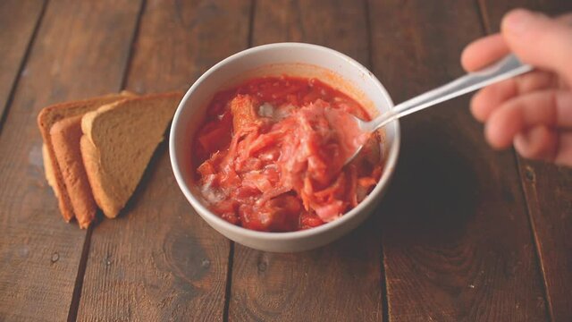 traditional ukrainian dish borscht with sour cream and bread on a wooden table