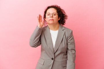 Business woman with Down syndrome isolated on pink background trying to listening a gossip.