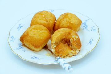 Homemade cupcakes filled with honey on a white and blue plate on a white background.