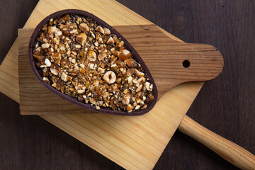 Top view of a stuffed hazelnut and chocolate easter egg on a wooden stand on a wooden table.