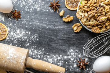 Bakery background. Cooking food ingredients: flour, eggs, nut and star anise, orange on dark table kitchen background for cake. Kitchen Food Frame.