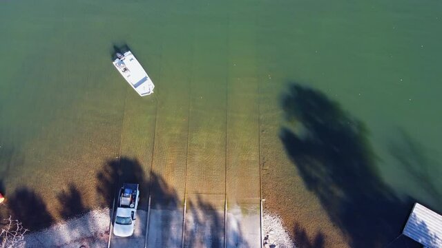 Pickup truck pulling boat and trailer out of the water at the shore of a lake