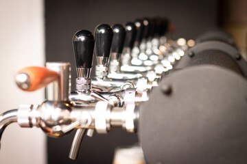 Partially blurred silvery bar beer taps in pub