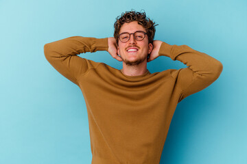 Young caucasian man wearing eyeglasses isolated on blue background feeling confident, with hands behind the head.