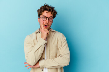 Young caucasian man wearing eyeglasses isolated on blue background having some great idea, concept of creativity.