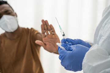 Syringe in the doctor’s hand and a refusing patient says NO