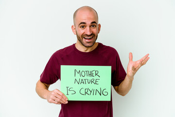 Young caucasian bald man holding a Mother Nature crying isolated on white background receiving a pleasant surprise, excited and raising hands.