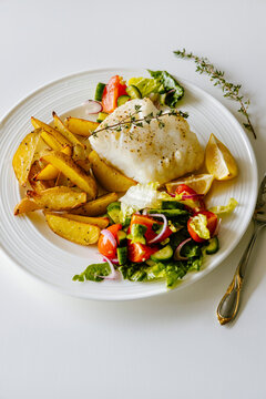 Oven baked chilean sea bass with herb roasted potatoes and fresh salad