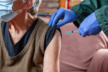 elderly woman receiving the vaccine at her house