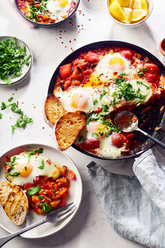 Top view breakfast Shakshuka with vegetables, herbs, tomato sauce and grilled bread slices