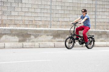 Fototapeta na wymiar Man driving electric bike to work with dark sunglasses