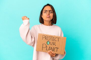 Fototapeta na wymiar Young hispanic mixed race woman holding a protect our planet cardboard showing fist to camera, aggressive facial expression.