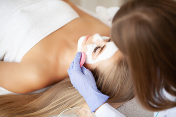 Naklejka premium Spa Woman applying Facial cleansing Mask, Beauty Treatments