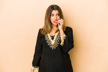 Young indian woman wearing traditional clothes isolated biting fingernails, nervous and very...