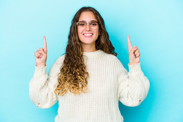Young caucasian curly hair woman isolated indicates with both fore fingers up showing a blank space.