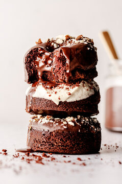 Baked dontus layered in a pil with chocolate glaze and cashew cream frosting, and with melted chocolate in a jar and dripping from them.