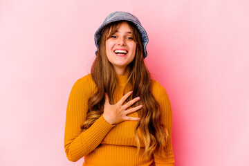 Young caucasian woman wearing fishermans hat isolated laughs out loudly keeping hand on chest.
