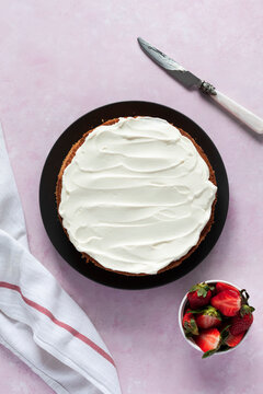 Victoria sponge cake topped with mascarpone cream with fresh strawberries on the side.