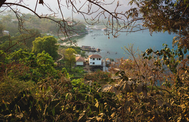 Aerial view on village coast along lake Atitlan through trees, San Juan la Laguna, Guatemala