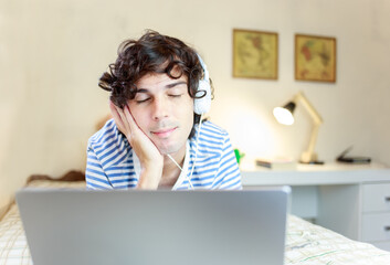 Young man lying in the bedroom and using headphones to listen to ASMR or listen to music.