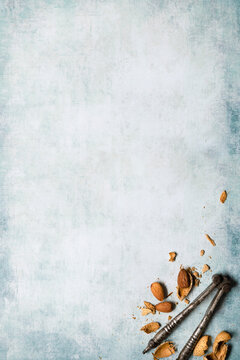 Cracked almonds and nutcraker in the corner of a blue textured background.
