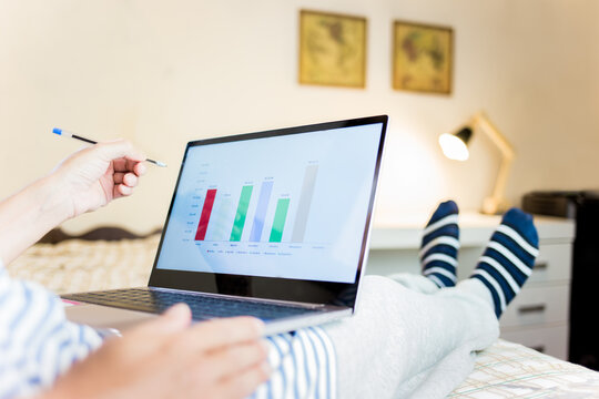 Man sitting comfortably at home, wearing socks on his feet and using his laptop to work at home. Homeoffice concept. Analyzing graphics on a computer screen.