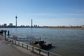 Outdoor sunny view promenade riverside and bridge toward pier, pontoon or buoy over Rhine River and...