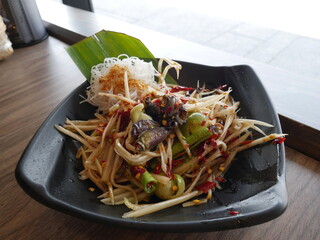 Spicy papaya salad (Somtam) mixed with local pickled fish, chilly and lime juice serving on the plate. 