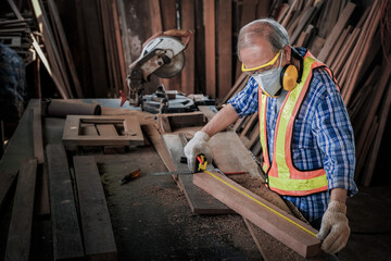 Carpenter men work on the measurements of wood in a carpentry shop.