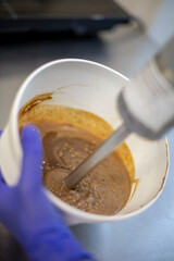 Female confectioner mixing ingredients use blender for preparation sweet pastry cream or dough