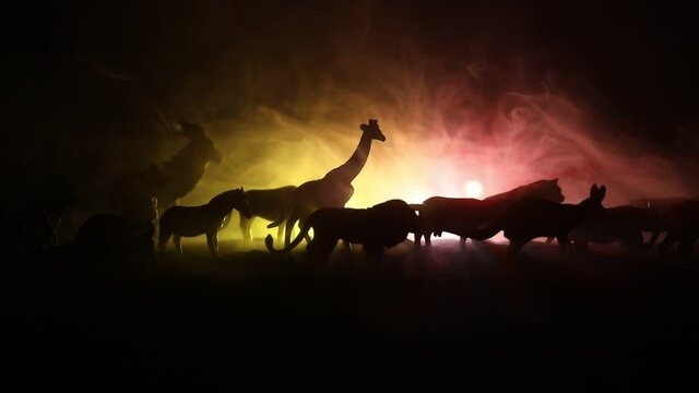 A group of animals are grouped together at foggy night with burning colorful background. Animals Running Escaping to Save Their Lives from fire. Selective focus.