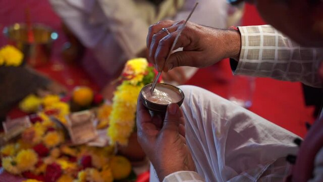 hands of a Hindu priest doing a religious ritual with wood and curd during wedding ceremony in India, asia