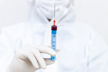 Hand of nurse, doctor or medical technologist in white gloves with  syringe taking blood sample from a patient in the hospital, Doctor drawing blood sample from arm for blood test.