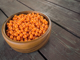 Ripe fresh sea buckthorn in wooden bowl on a wooden background. Top view. Flat lay