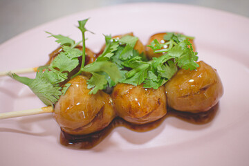 Thai pork balls with brown sweet sauce on plastic dish.