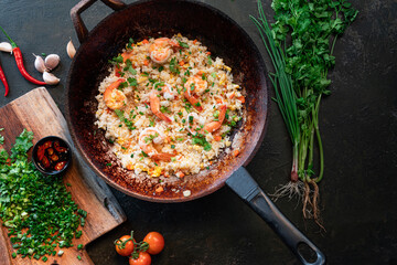 Asian fried rice with shrimp in black iron pan. Prepared in wok. Top view.