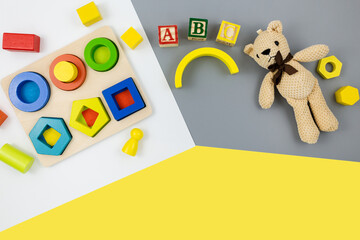 Wooden toys, blocks, bear on yellow gray background. Trendy cute baby first toys. Eco-friendly, plastic-free set of accessories for kids. Toys for kindergarten, preschool or daycare. Close up	