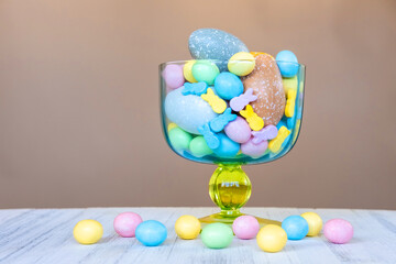 Easter sweet candies and pastel colored eggs in a beautiful glass vase. Easter celebration concept.