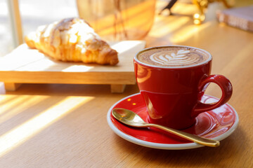 Close up hot cappuccino, latte on table with blur coffee shop background. Hot cappuccino coffee on wood table with blur croissant background. breakfast at coffee shop. softfocus select coffee