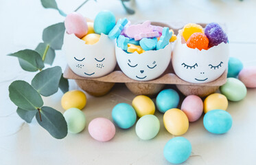 Fototapeta na wymiar Cute Easter eggs with funny faces full of sweet candies. Easter and spring celebration concept